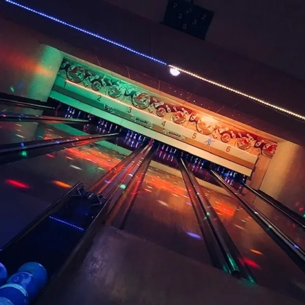 A six lane bowling alley with neon lights.